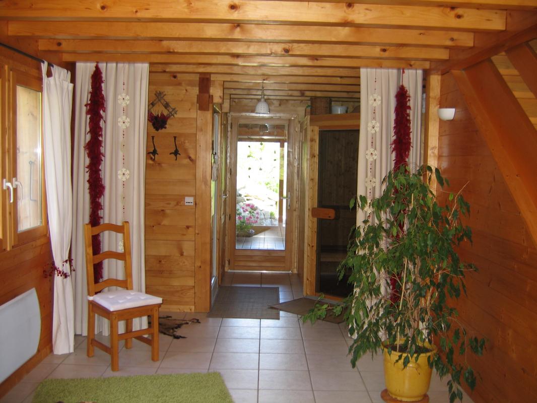 Vue de la salle de d&eacute;tente avec le sauna en fond et aper&ccedil;u du spa derri&egrave;re la porte vitr&eacute;e.